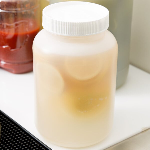 A Carlisle plastic container with a white cap filled with red liquid sitting on a counter.