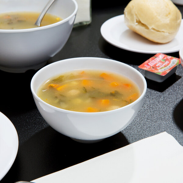 A table with GET white melamine bowls of soup and bread.