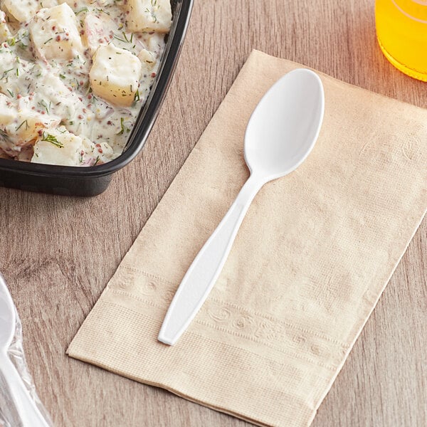 A white plastic Visions teaspoon next to a bowl of potato salad.
