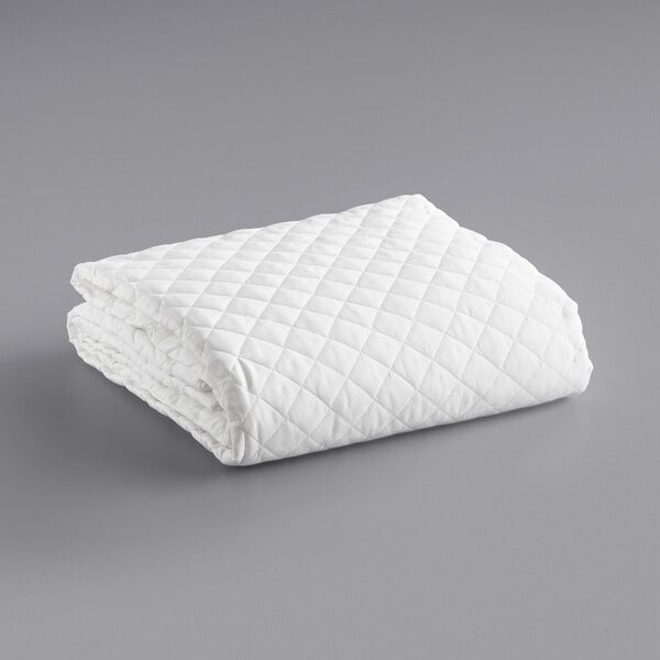 A white quilted blanket on a gray surface.