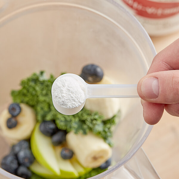 A hand holding a spoon with Add A Scoop Multi-Vitamin Blend Supplement powder in it.