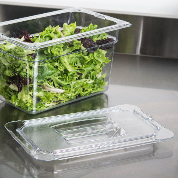 A Carlisle clear plastic lid on a container of lettuce.