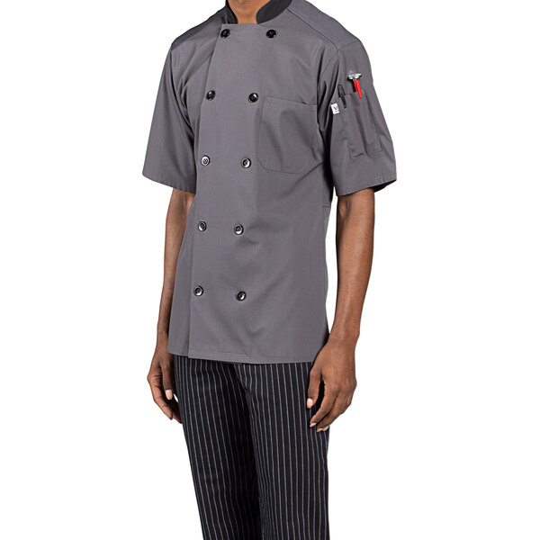 A man wearing a Uncommon Chef slate short sleeve chef coat with mesh back.