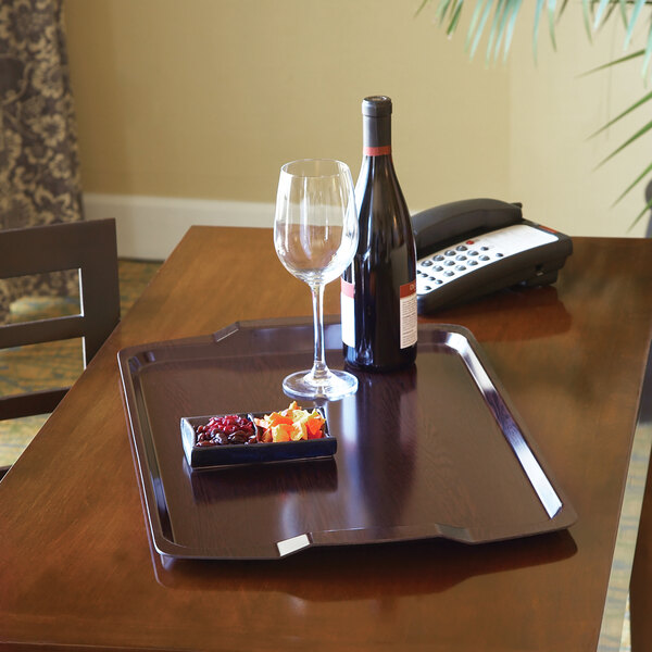 A Cambro hotel room service tray with food, a wine glass, and a wine bottle on it.