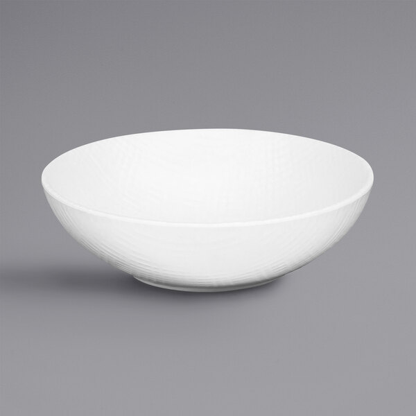 A Cal-Mil Sedona textured white melamine bowl with a curved edge.