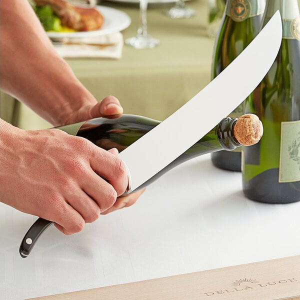 A person using a Della Luce Ebony Champagne Saber to open a bottle of wine.
