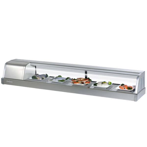 A Turbo Air stainless steel curved glass refrigerated sushi case on a counter with trays of food inside.