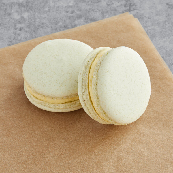 Two white Macaron Centrale cookies with yellow filling on a brown napkin.