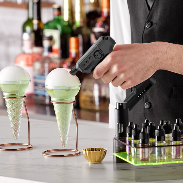 A bartender uses a Flavour Blaster Jet Black Mini Cocktail Gun to add flavors to a cone of ice cream.