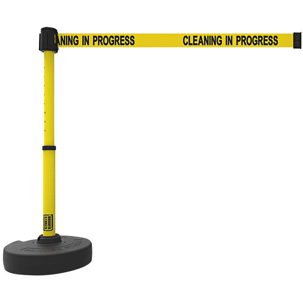 A yellow Banner Stakes PLUS retractable barrier tape with black text reading "Cleaning in Progress" and a black round and yellow handle.
