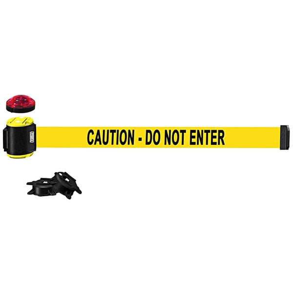 A yellow Banner Stakes wall mount belt barrier with a yellow caution tape and black text and a light kit.