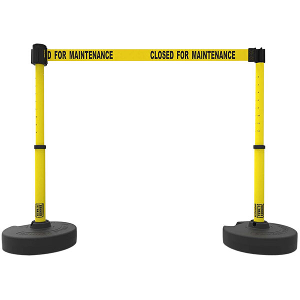 A pair of yellow and black Banner Stakes retractable barriers.