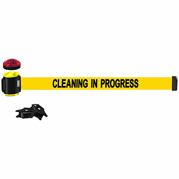 A yellow Banner Stakes wall mount belt barrier with black "Cleaning in Progress" text and a red light.