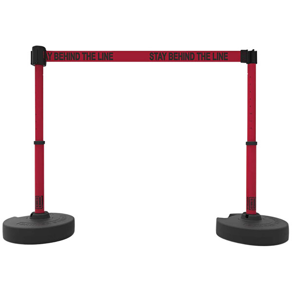 A pair of red and black Banner Stakes PLUS retractable barriers with a "Stay Behind The Line" sign.