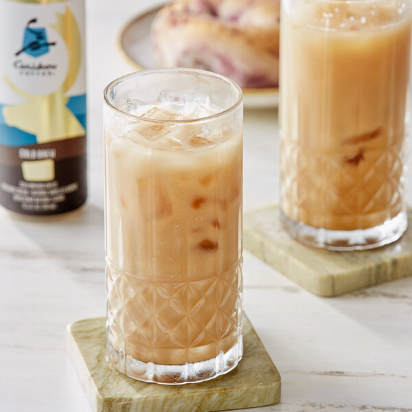 A glass of Caribou Vanilla Crafted Cold Brew Coffee with ice and a straw.
