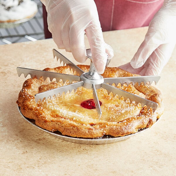A person using a Choice aluminum pie and cake marker to cut a pie.