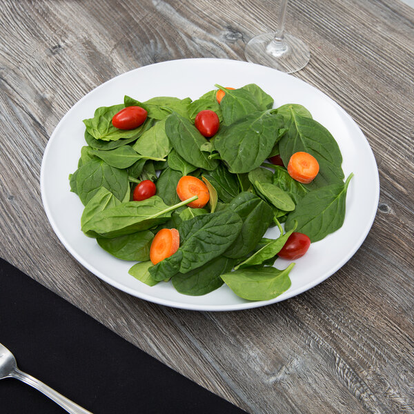 A white Siciliano plate with a salad of tomatoes and spinach.