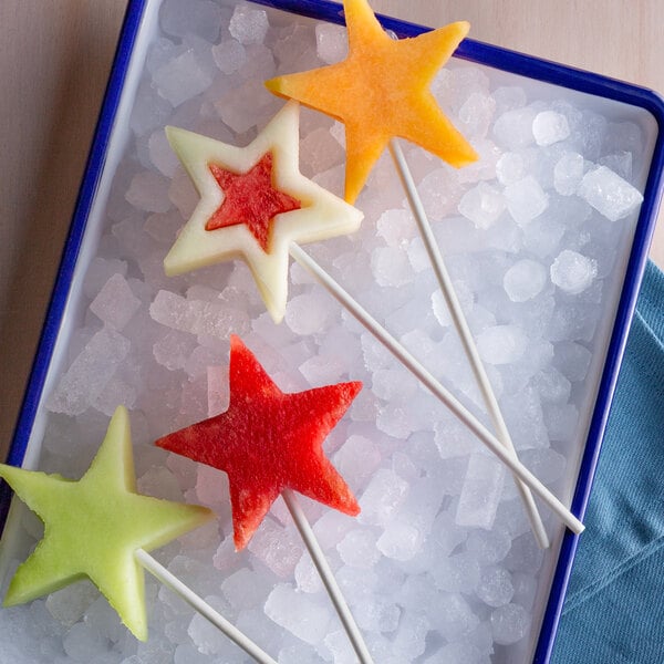A tray of star shaped watermelon on paper lollipop sticks.