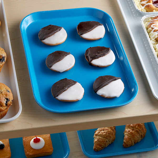A blue Cambro market tray of pastries and cookies on a bakery display counter.