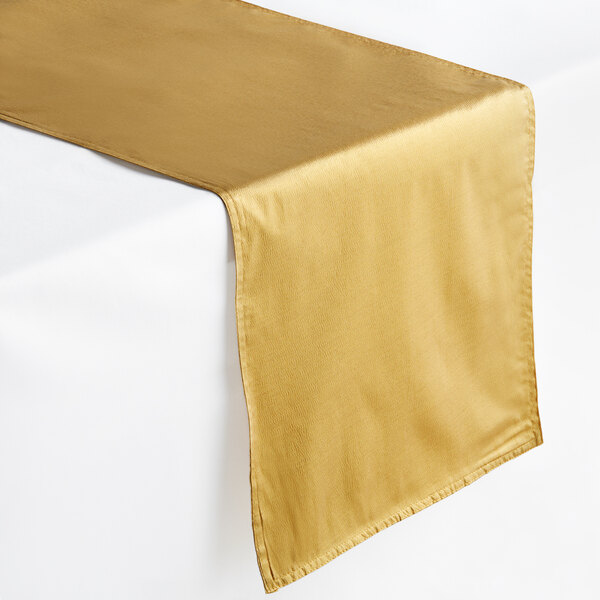 An Amscan gold satin table runner on a white table.