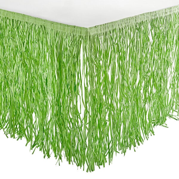 An Amscan green grass table skirt on a white table.