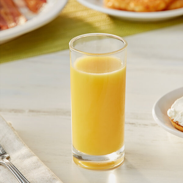 A glass of Ocean Spray orange juice on a table next to food.