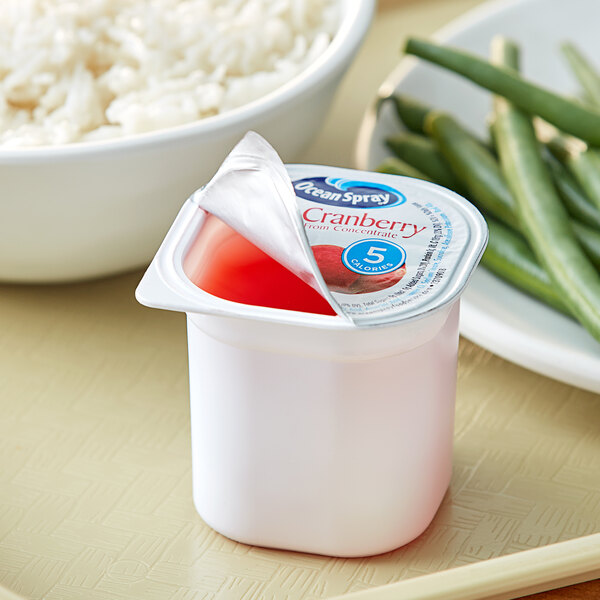 A white container with a red liquid and a red lid.