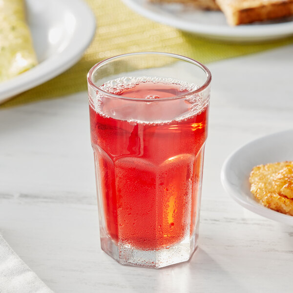 A glass of Ocean Spray cranberry juice on a table with food.