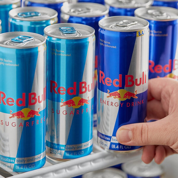A person holding a blue and silver Red Bull can.