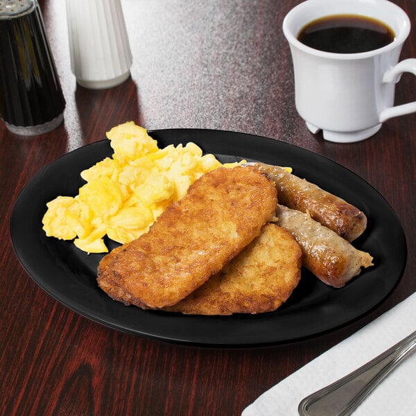 A black oval platter with food including eggs, sausage, and toast on it.
