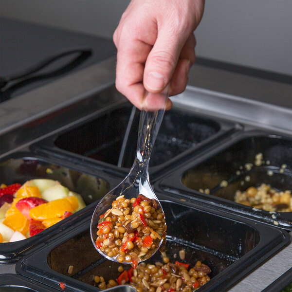 A hand using a Sabert clear plastic serving spoon to dish food into a container.