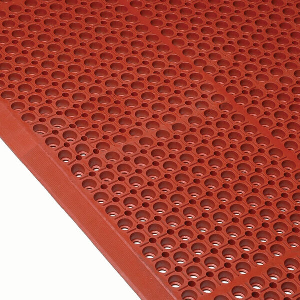 A close-up of a red Cactus Mat with holes in it.