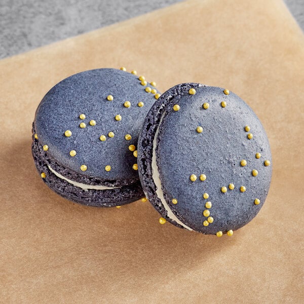 Two blue Macaron Centrale macarons with yellow dots on them.