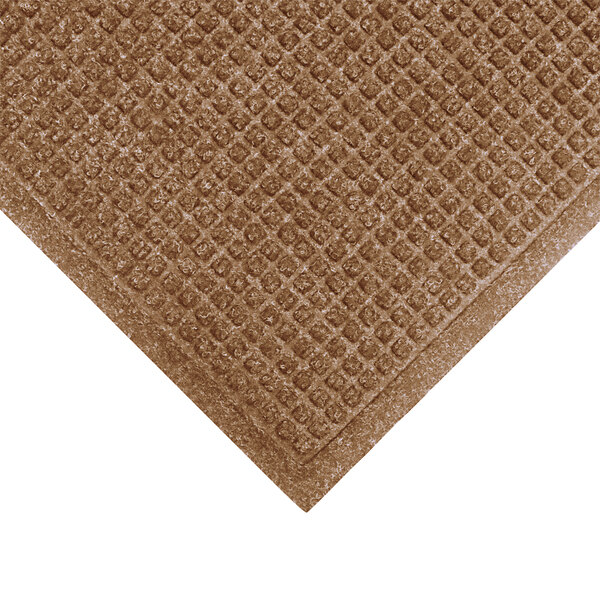 A close-up of a brown M+A Matting WaterHog mat with a square pattern and smooth backing.