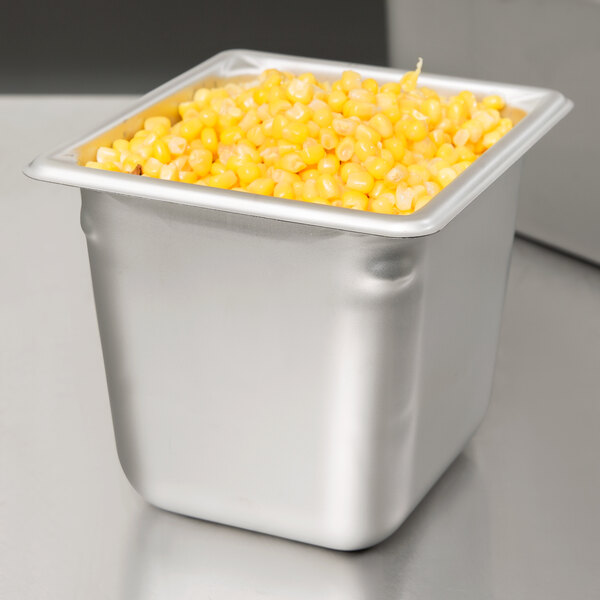 A Vollrath stainless steel pan full of corn kernels on a counter.