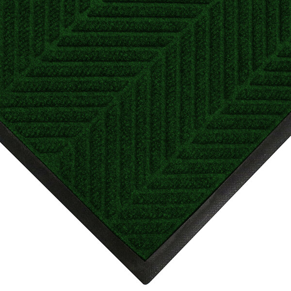 A green WaterHog mat with black trim and a pine design.