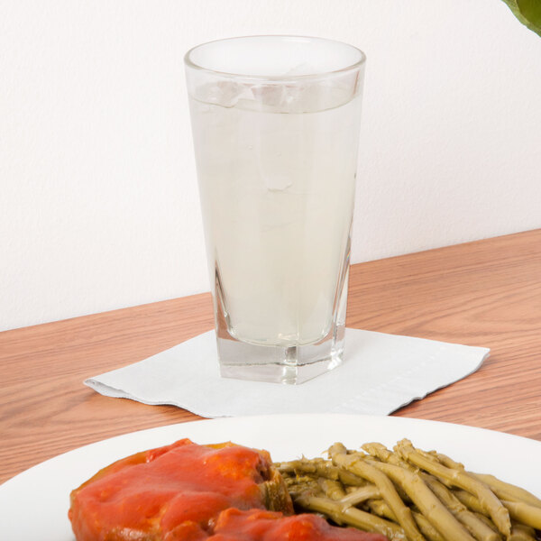 A Libbey Inverness beverage glass of water on a table with a plate of food.