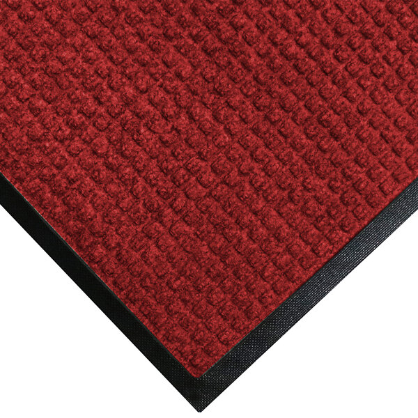 A red WaterHog Classic doormat with black trim.