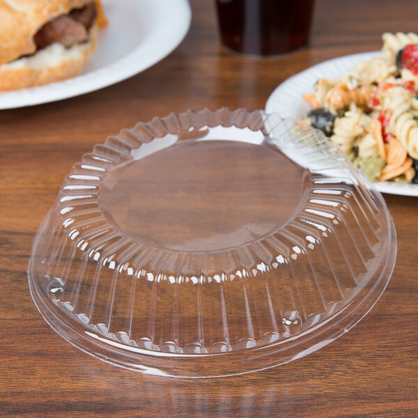 A clear Dart plastic dome lid on a clear plastic container on a table.