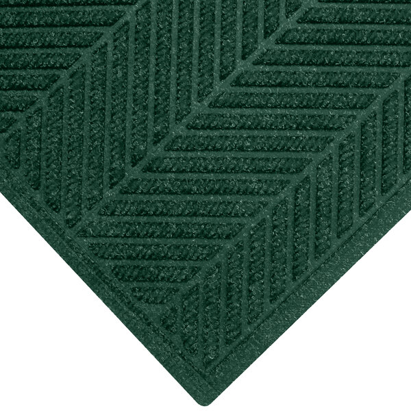 A close-up of a green WaterHog mat with a chevron pattern border.