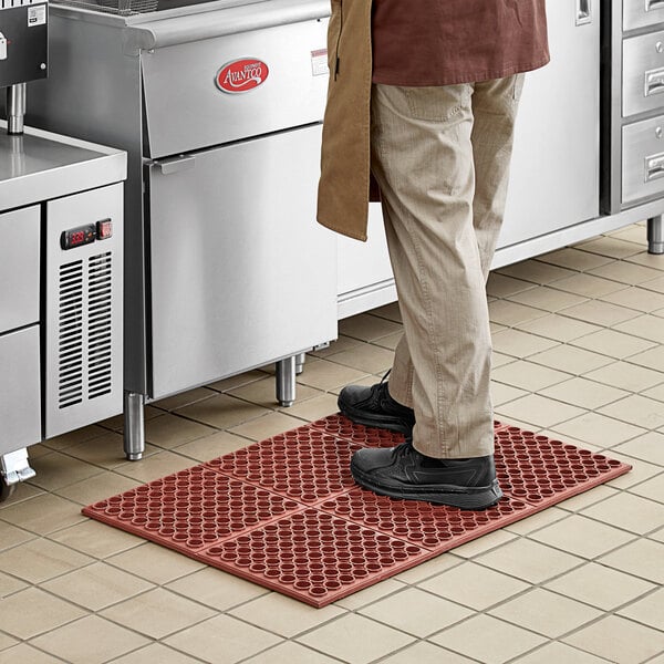 A man standing on a red Choice anti-fatigue floor mat.