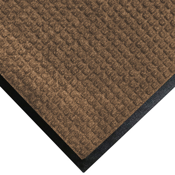 A close-up of a brown M+A Matting WaterHog mat with a black rubber border.