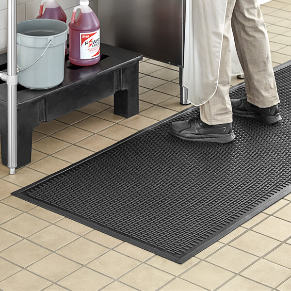 A person standing on a black Choice rubber mat.