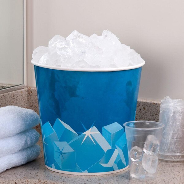A Lavex disposable paper ice bucket filled with ice on a table in a hotel room.