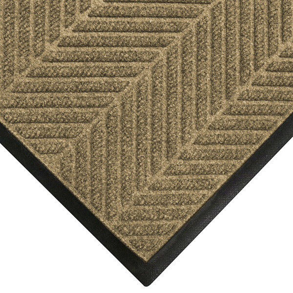 A khaki WaterHog entrance mat with a classic border and black chevron pattern.