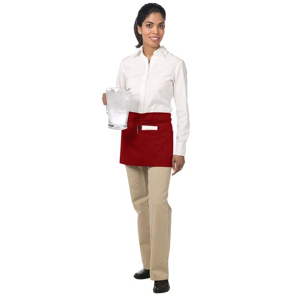 A woman wearing a red Chef Revival waist apron holding a glass of ice.