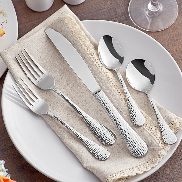 A plate with Acopa Inspira stainless steel flatware on a napkin.