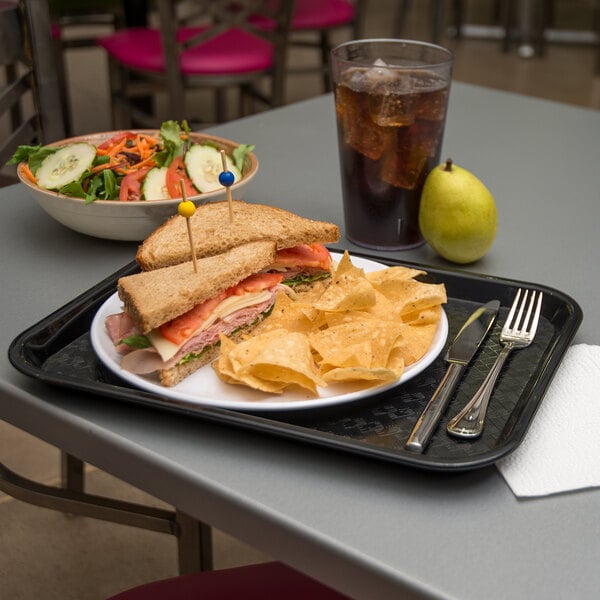 A Carlisle black plastic fast food tray with a sandwich and chips on it.