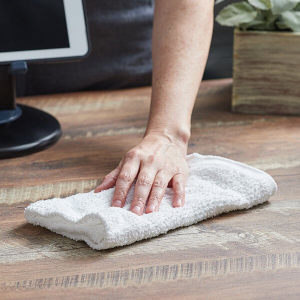 A hand wiping a counter with a white Choice bar towel.