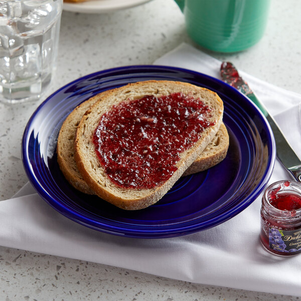 A Tuxton Concentrix cobalt plate with a piece of bread and jam on it.